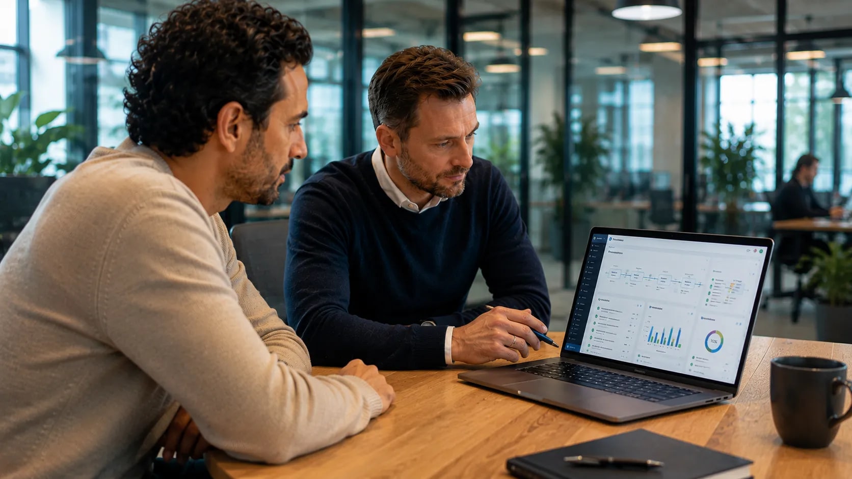 Two professionals discussing a software dashboard on a laptop, focusing on the manageability of AI-assisted development.