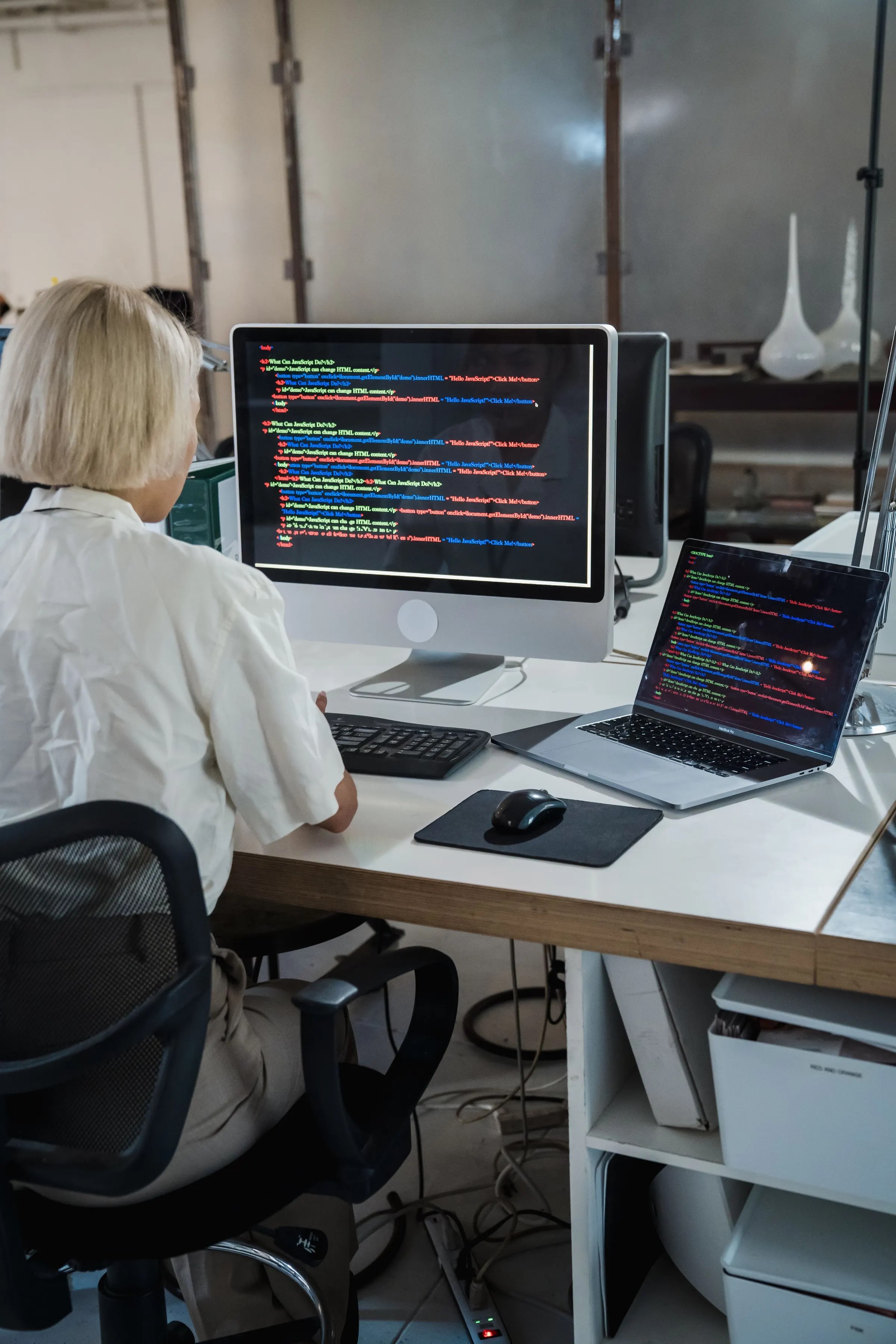 A developer working on code on a desktop and a laptop