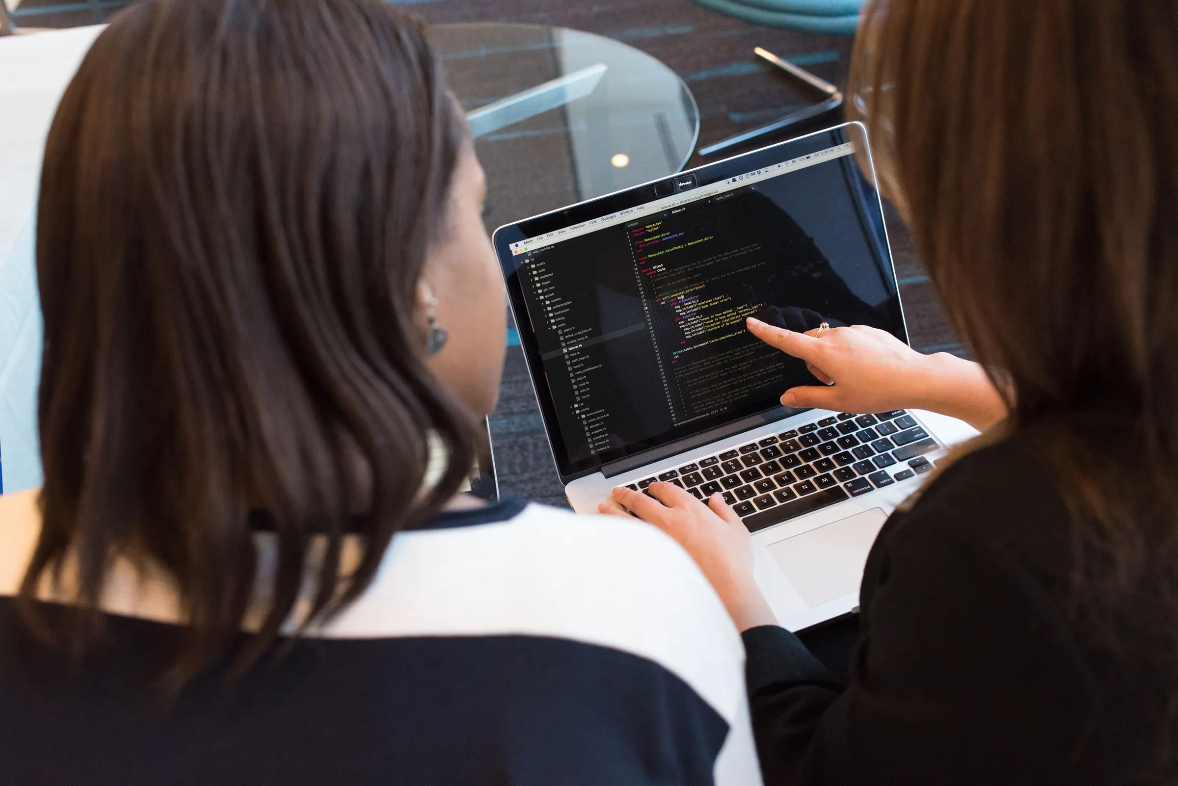 Twee ontwikkelaars bekijken samen code op een laptop, waarvan een naar het scherm wijst