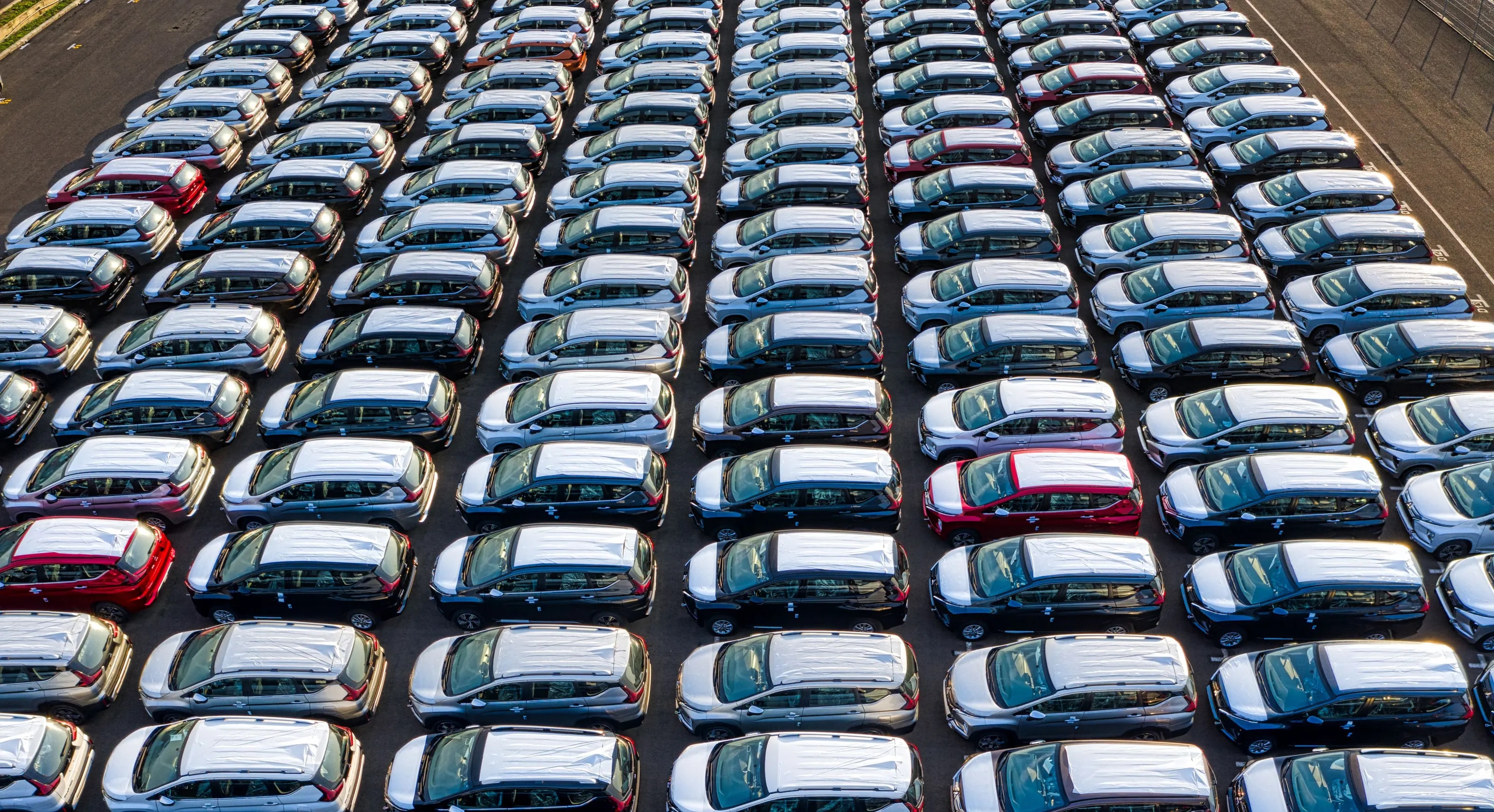Rows of new cars on a distribution lot, seen from above