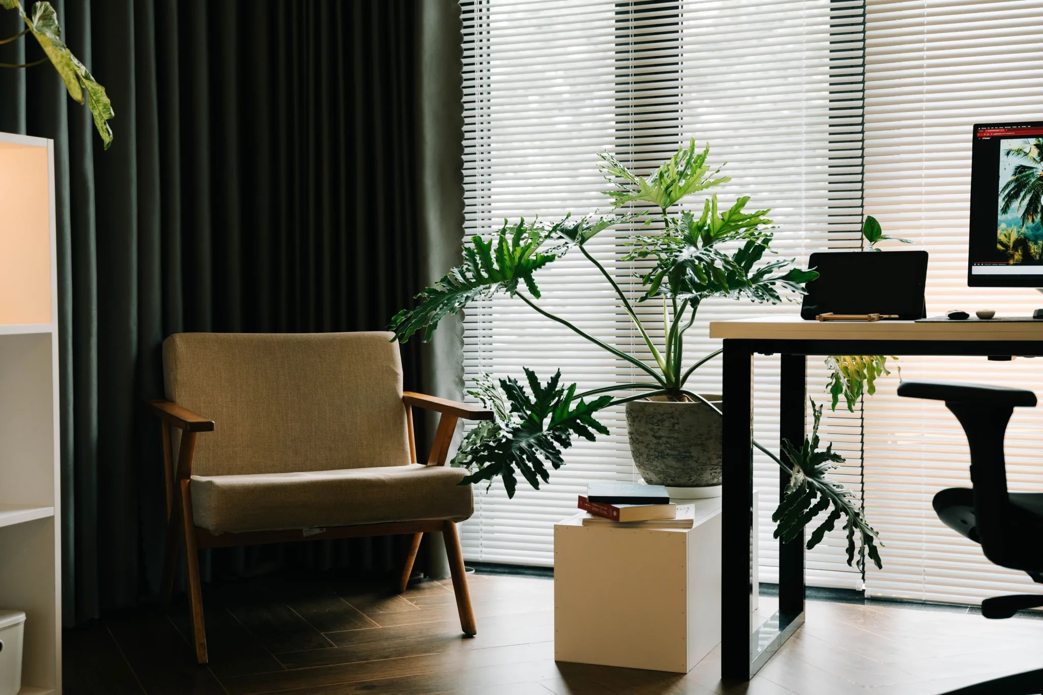 Lichte werkplek met een fauteuil, planten en een bureau met beeldscherm bij het raam