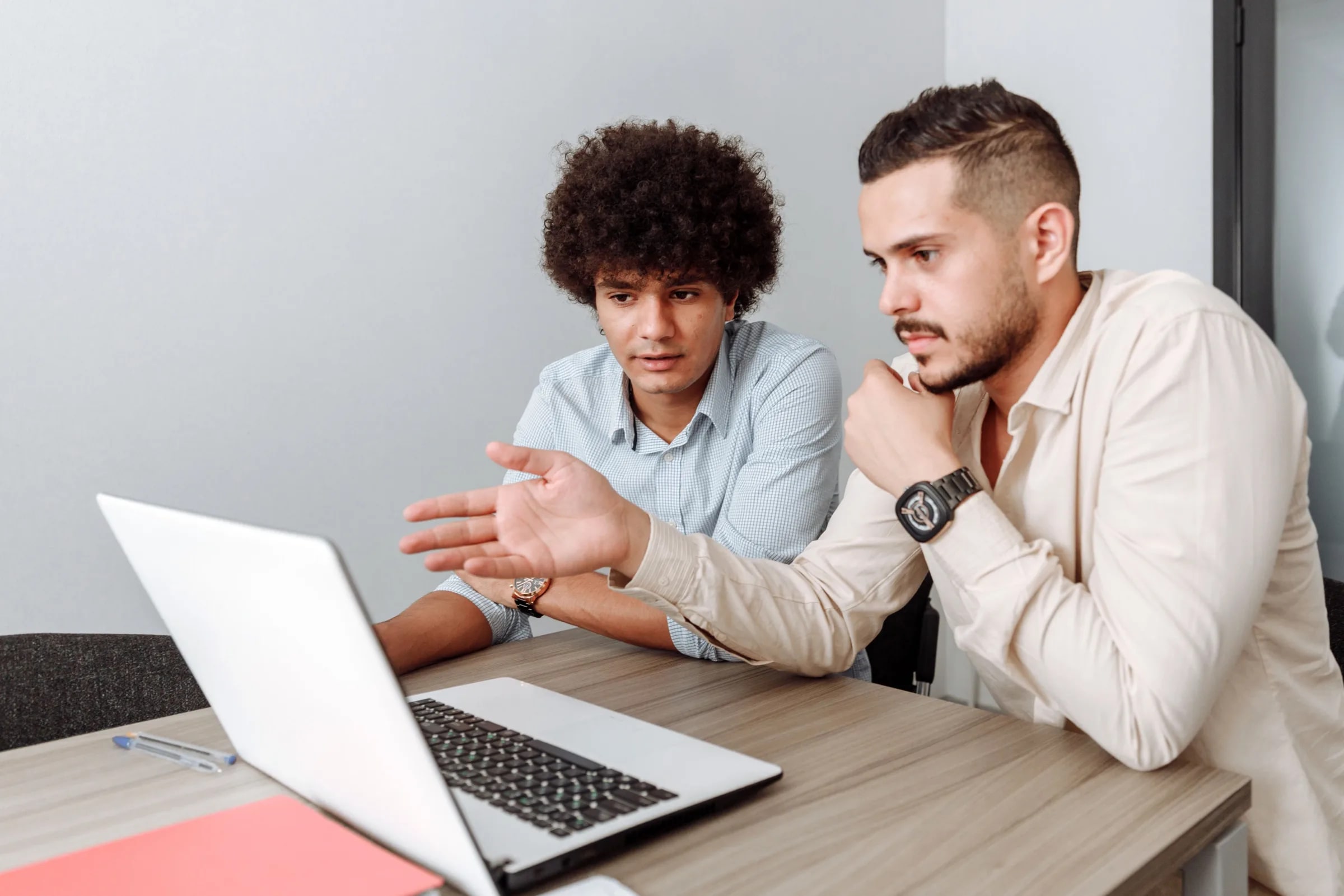 Two colleagues discuss something together on a laptop at a meeting table