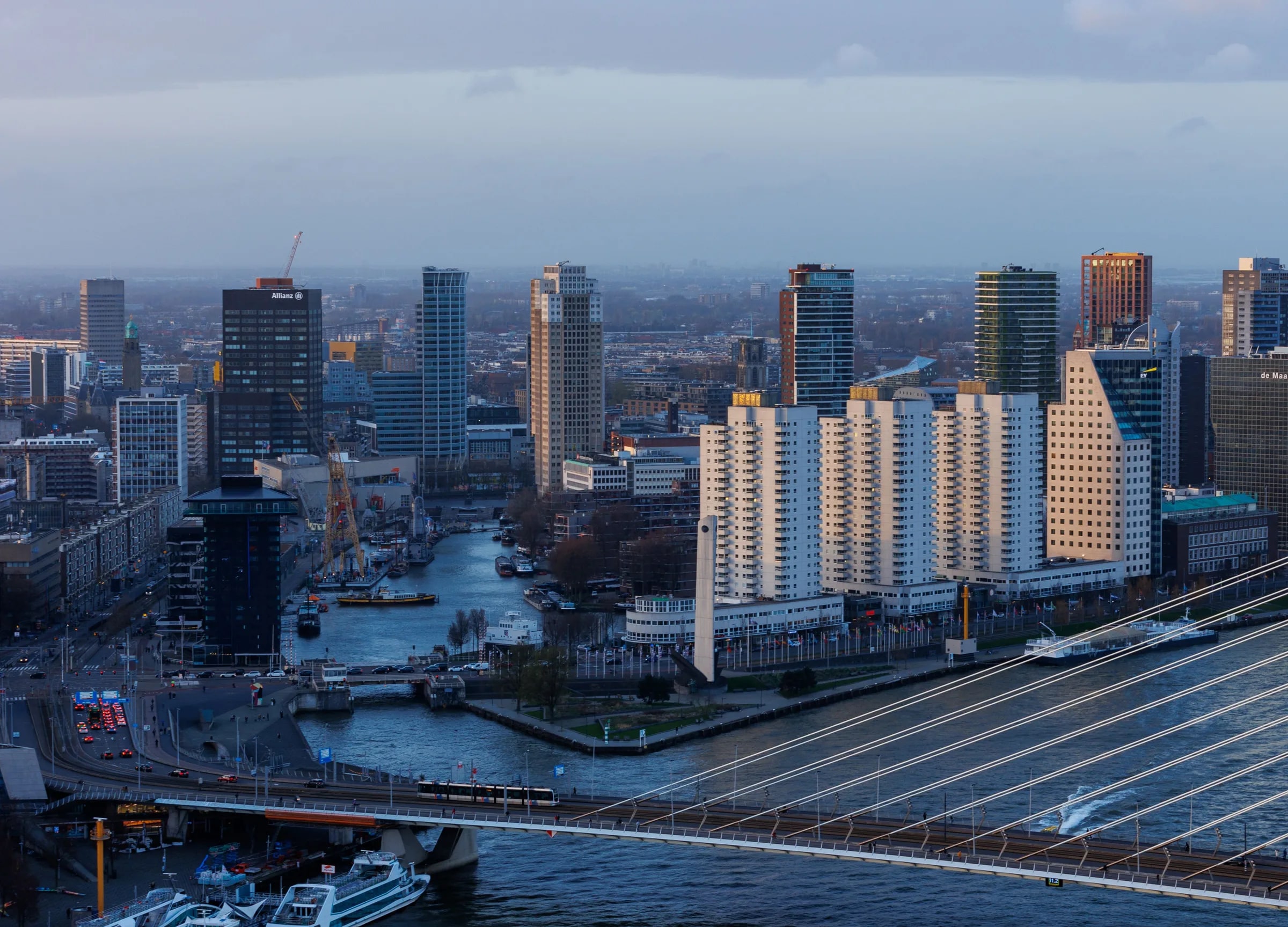 De skyline van Rotterdam bij de Maas, gezien vanaf de Erasmusbrug in het avondlicht