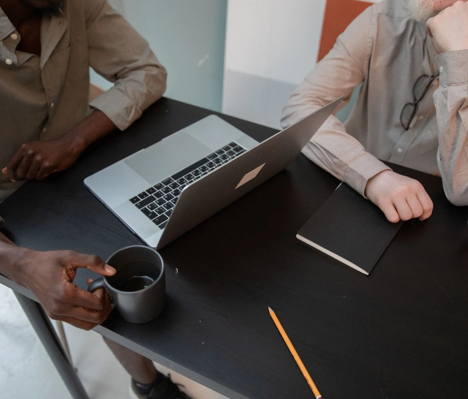 Two people discussing an app idea at a table with a laptop