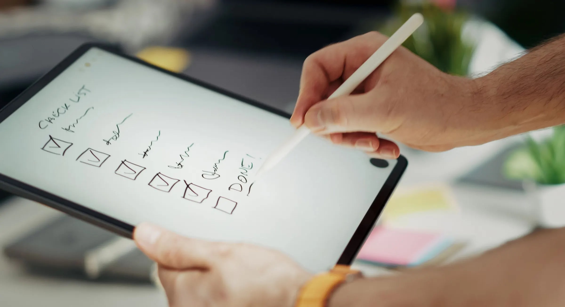 Hands ticking off a checklist on a tablet with a stylus