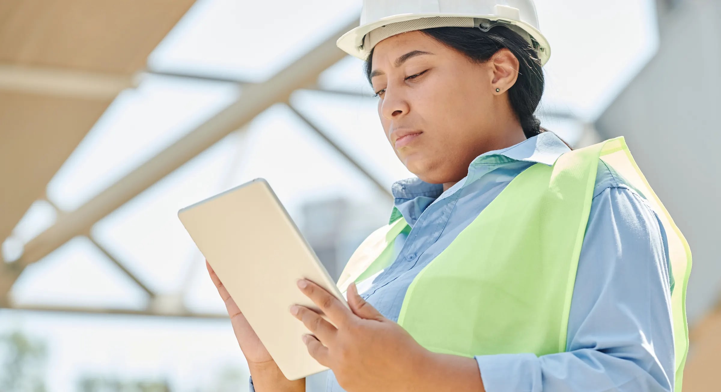 An engineer with a hard hat uses a tablet on site