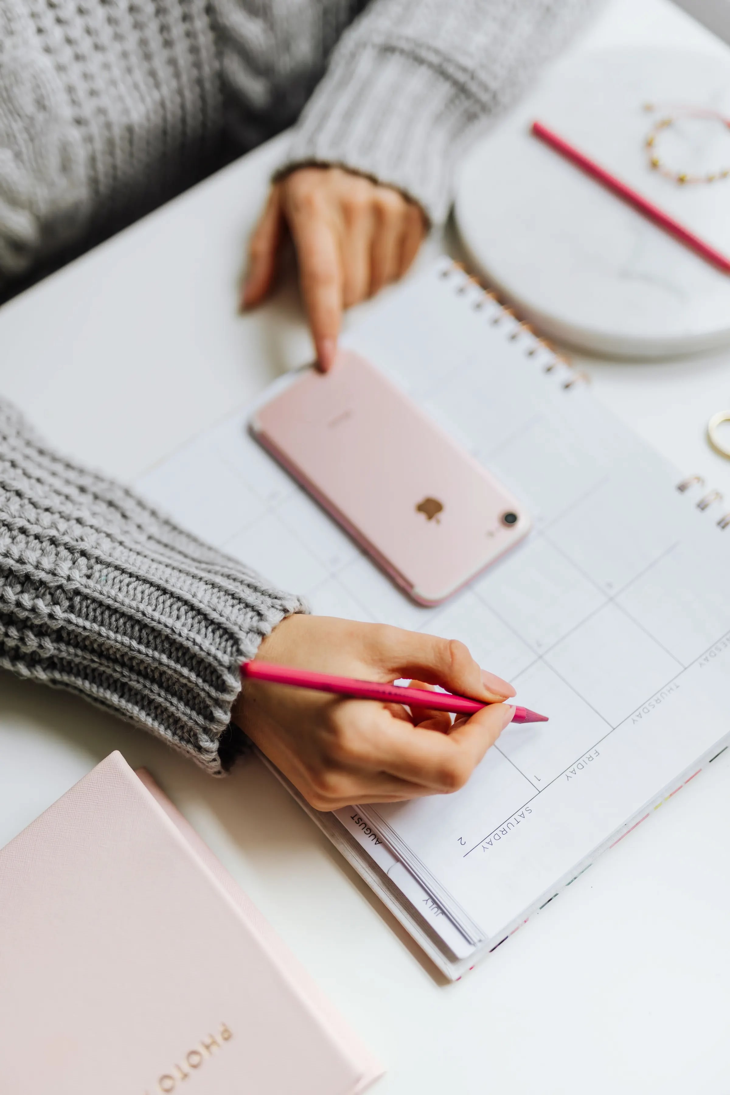 Someone planning appointments with a pen and a paper diary beside a phone