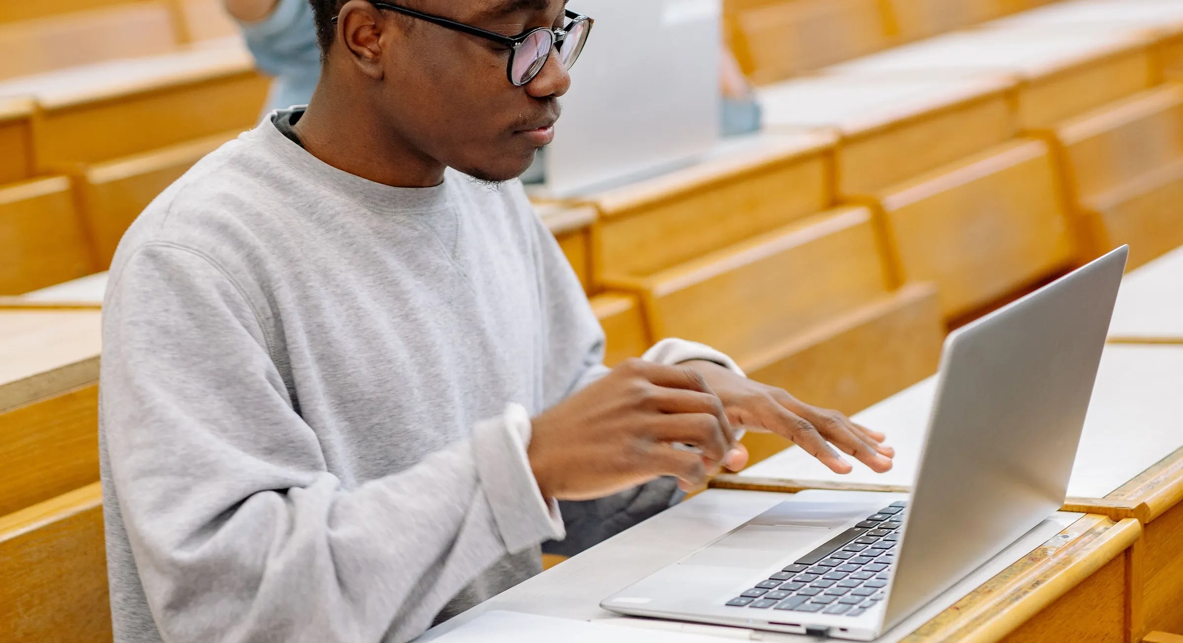 A student working on a laptop in a lecture hall
