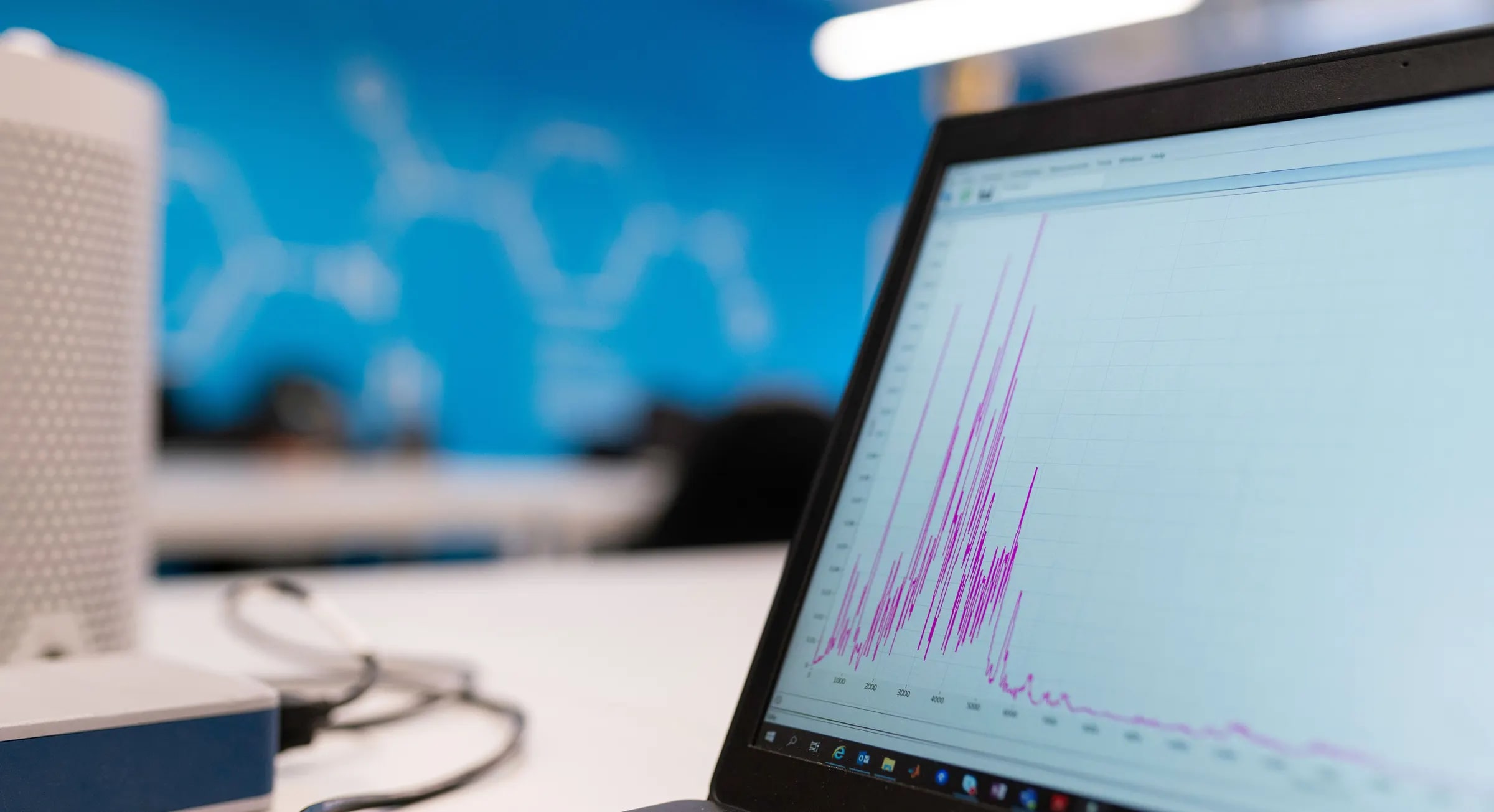 A laptop on a desk showing a graph on its screen
