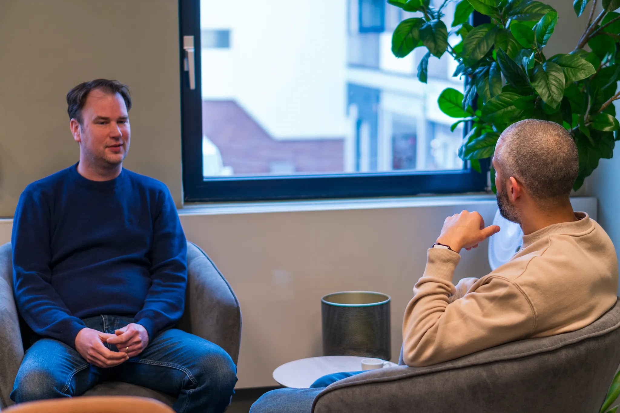 Two colleagues chatting by the window at the office