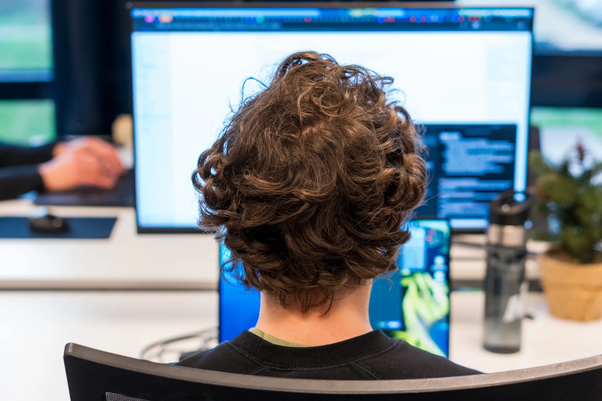 A developer working intently behind several screens of code