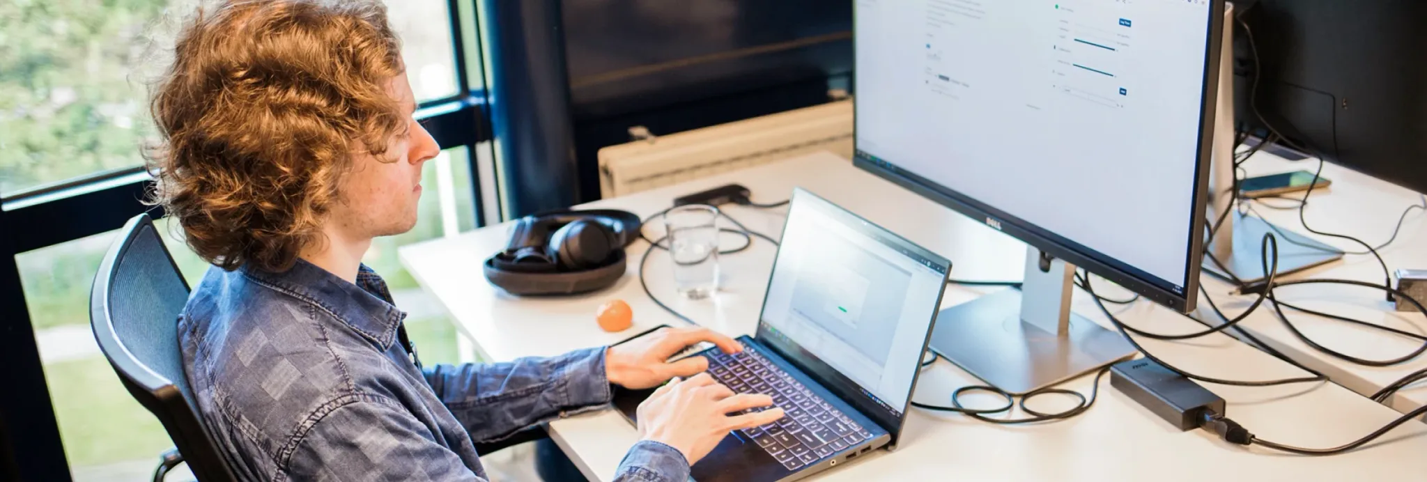 Een JAM-IT-collega aan het werk achter een laptop en een extra scherm
