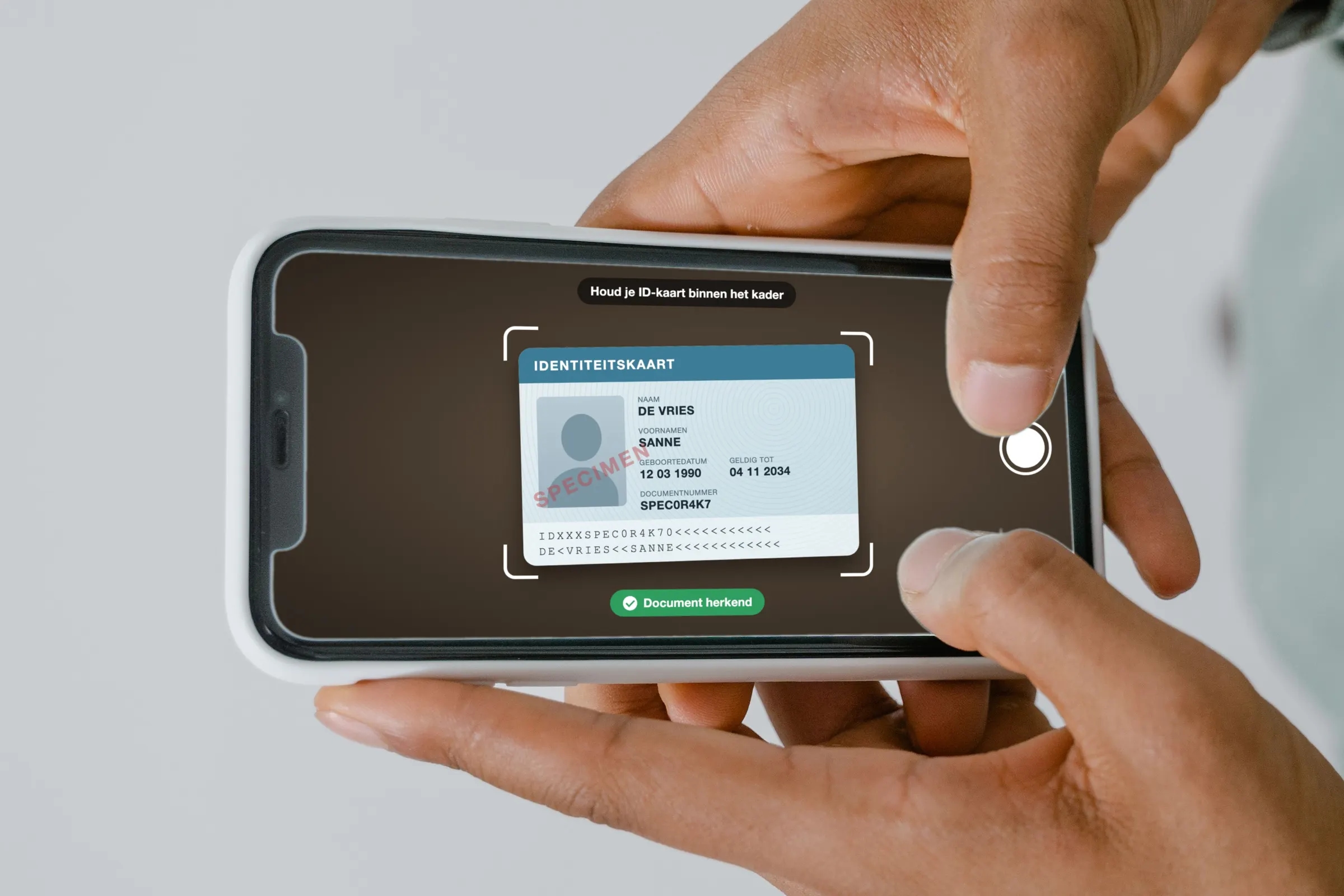 Someone photographing an identity card with a phone inside a scanning frame, with a message that the document has been recognised