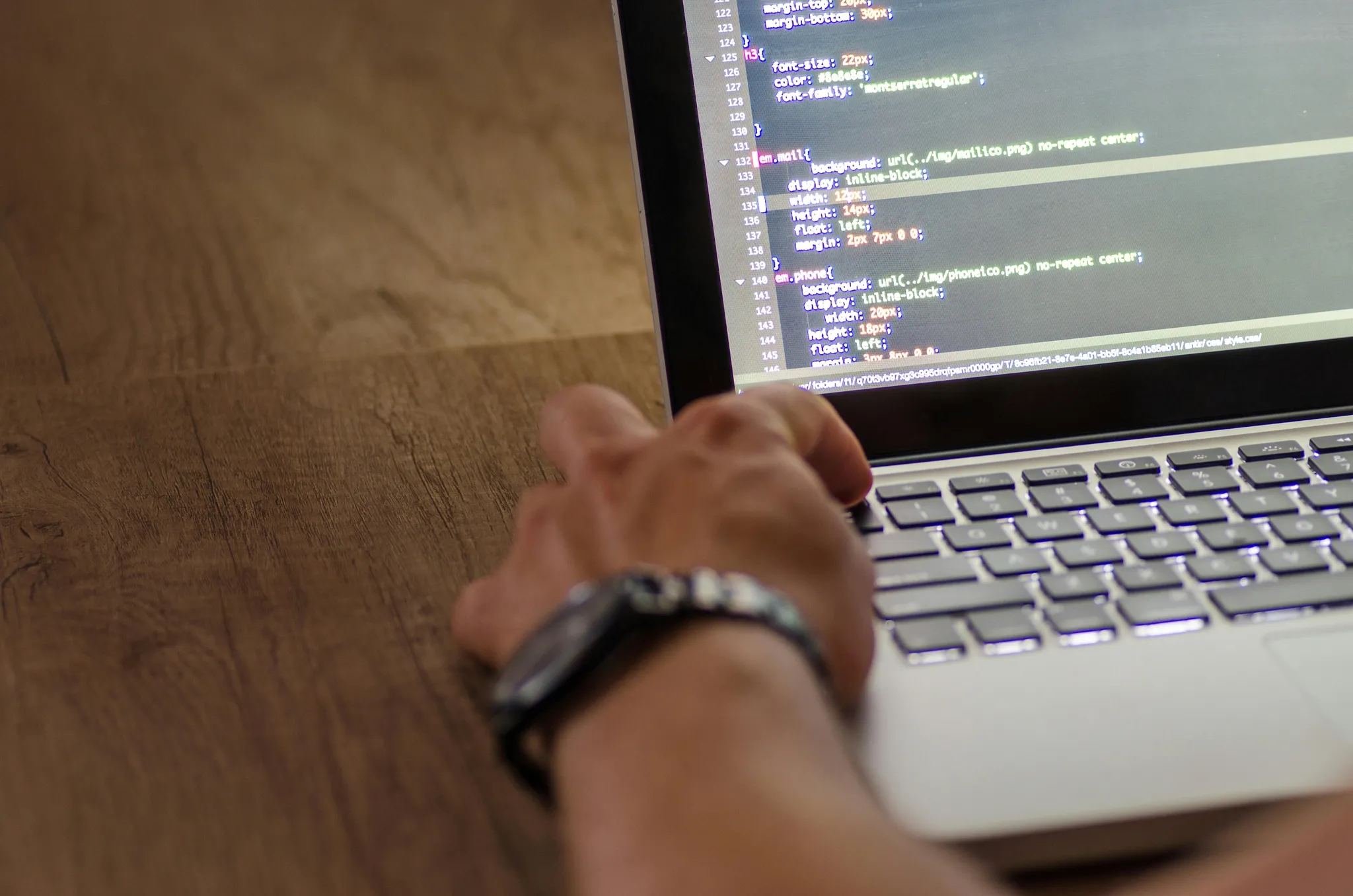 Someone programming on a laptop with code on the screen