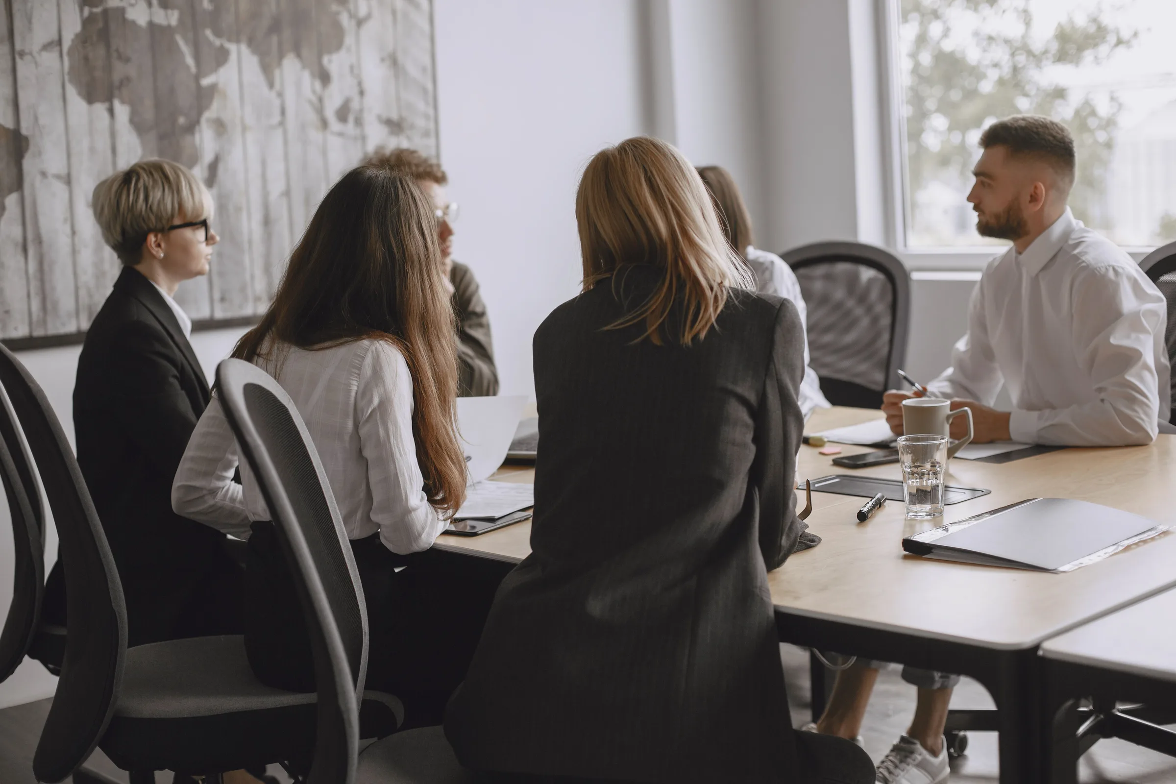 Een team zit in overleg rond een vergadertafel met laptops en documenten