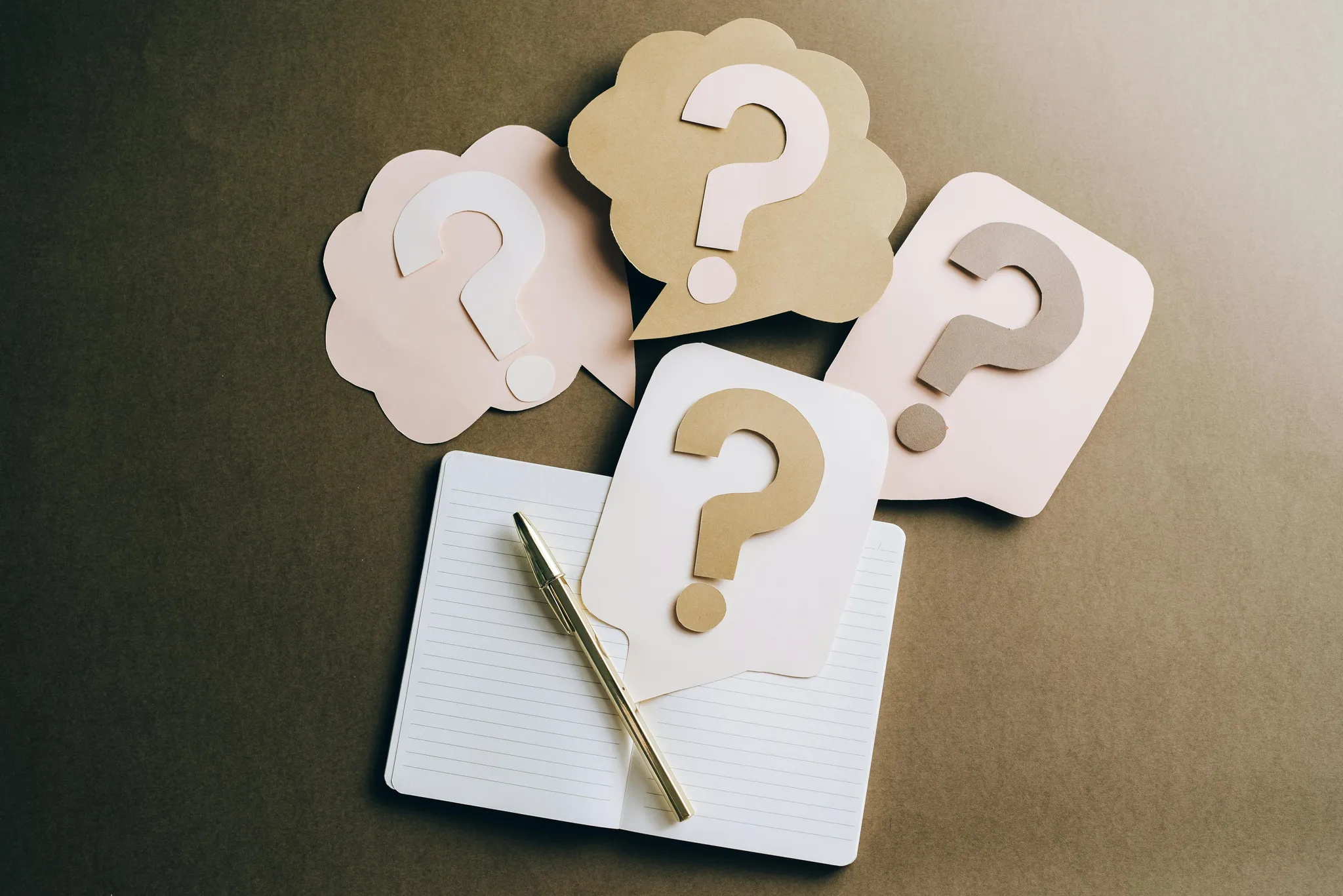 Paper clouds with question marks on a notebook
