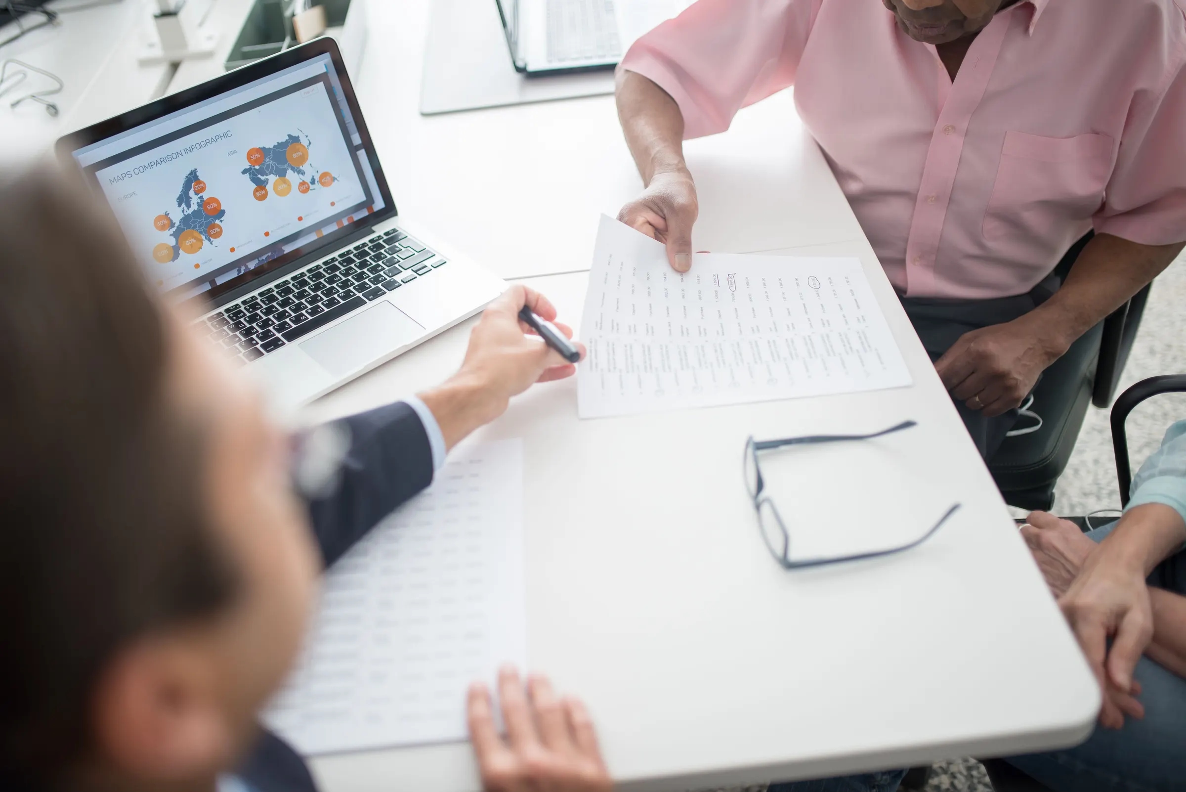 Een adviseur neemt een document door met een ouder echtpaar aan een bureau