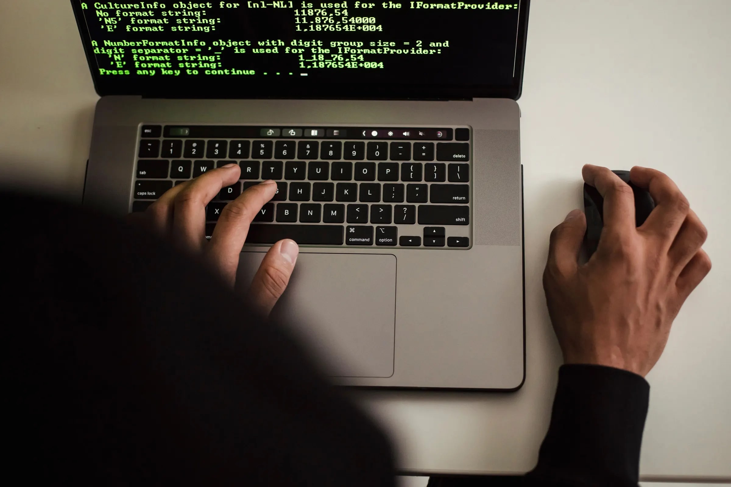 Iemand typt op een laptop met groene programmeertekst op het scherm