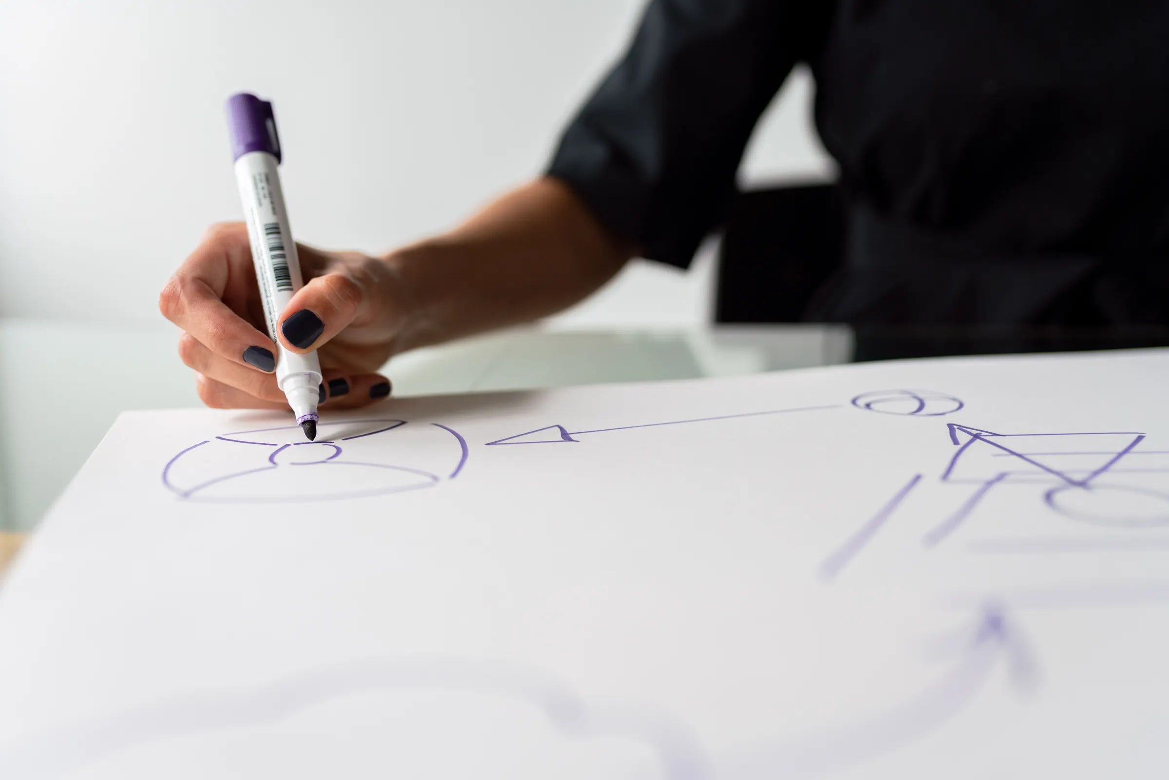Een hand tekent met een stift een schema met pijlen op een groot vel papier