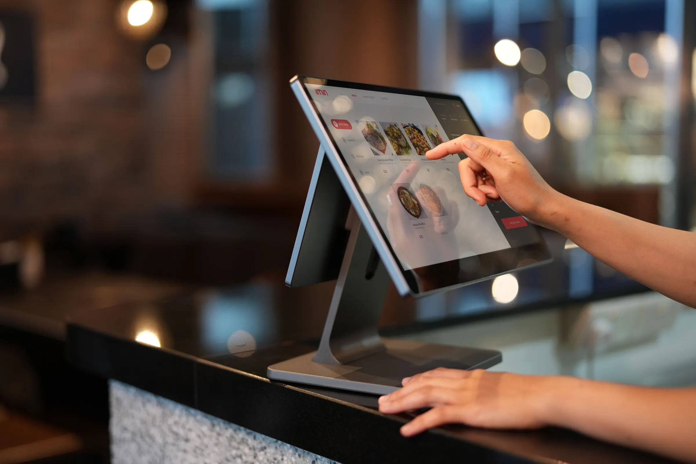 Een hand bedient het touchscreen van een kassasysteem