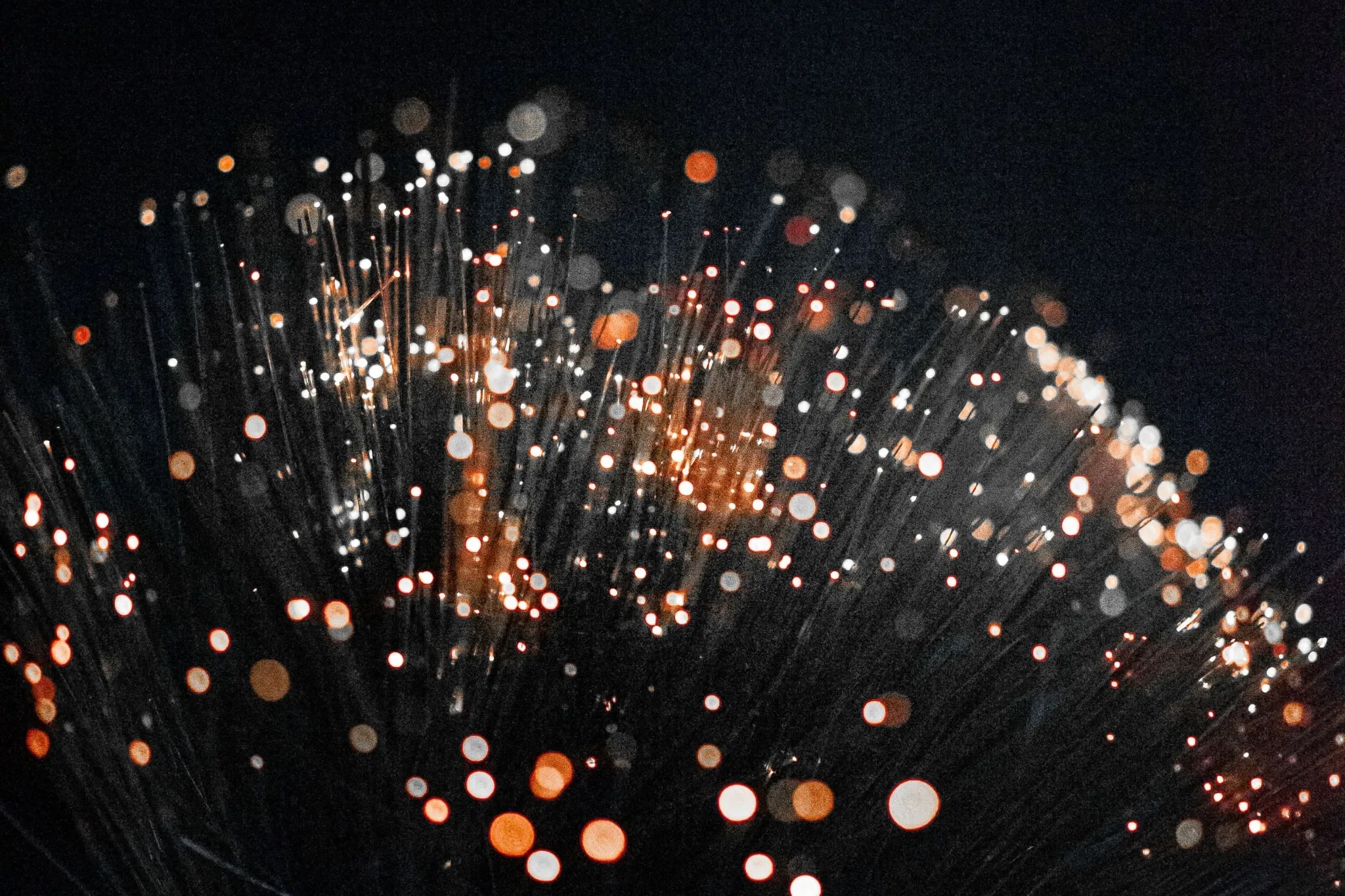 Glowing tips of optical fibres against a dark background