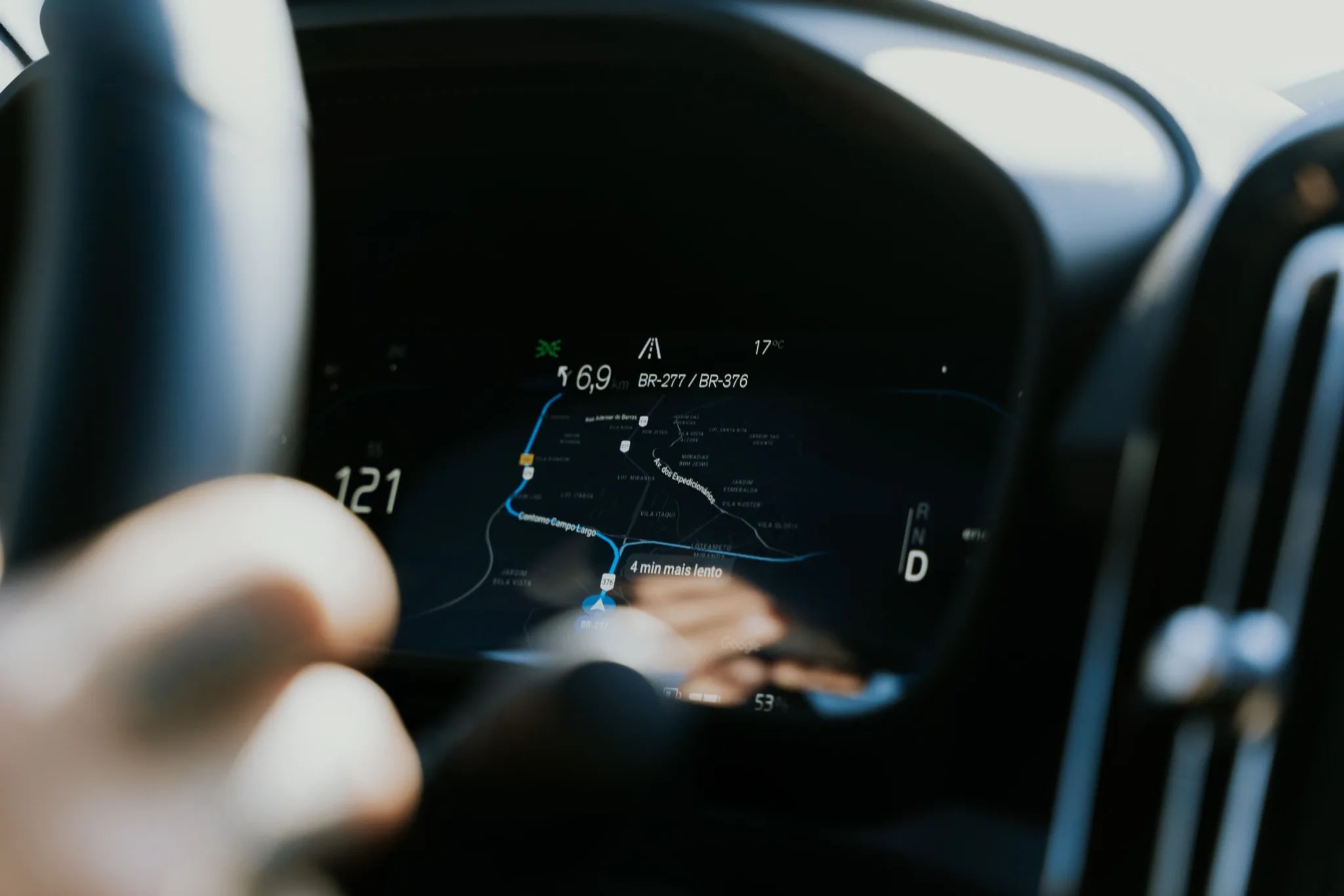 Navigation map on a car dashboard, a hand on the wheel
