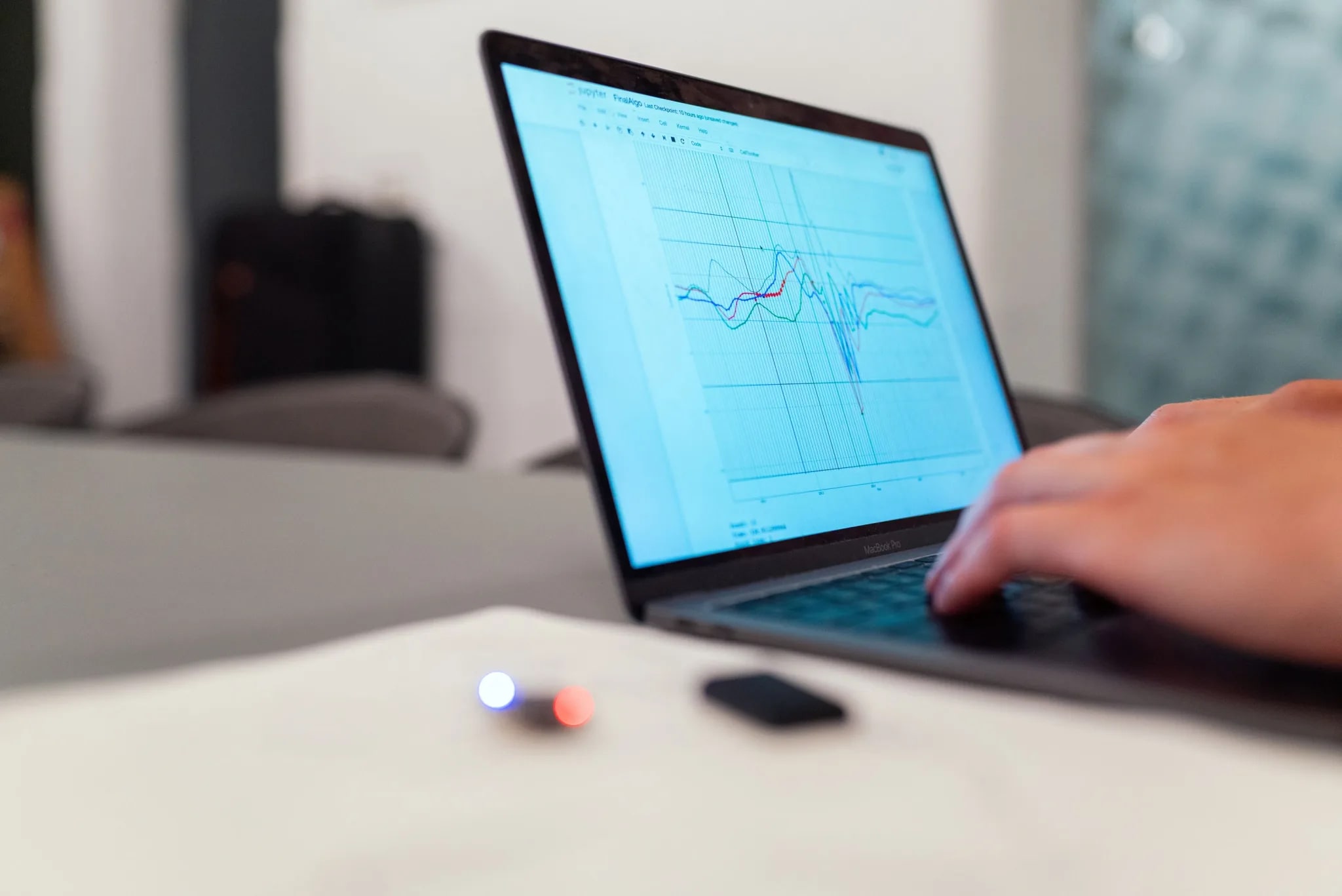 Hand on a laptop keyboard with charts on the screen