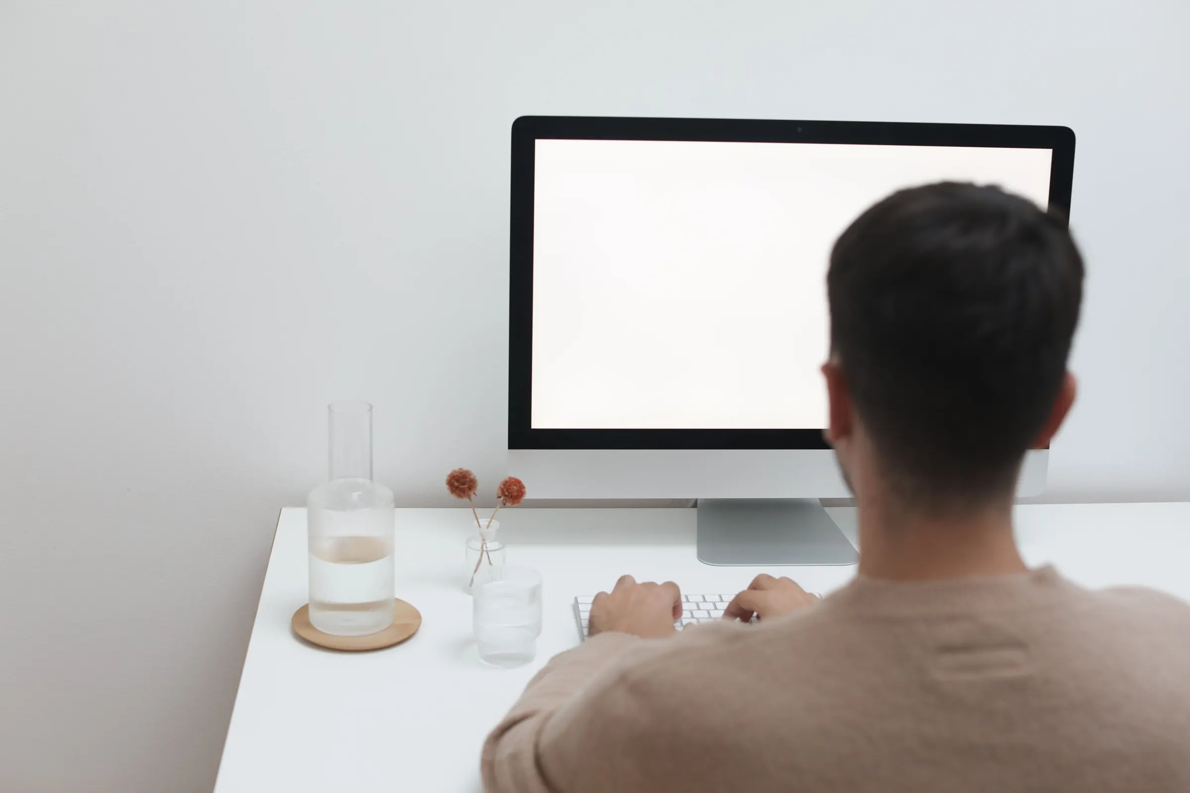 Een medewerker werkt achter een computer aan een opgeruimd bureau