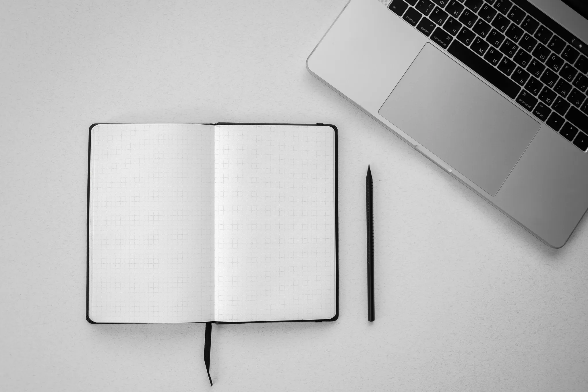 Leeg notitieboek met pen naast een laptop