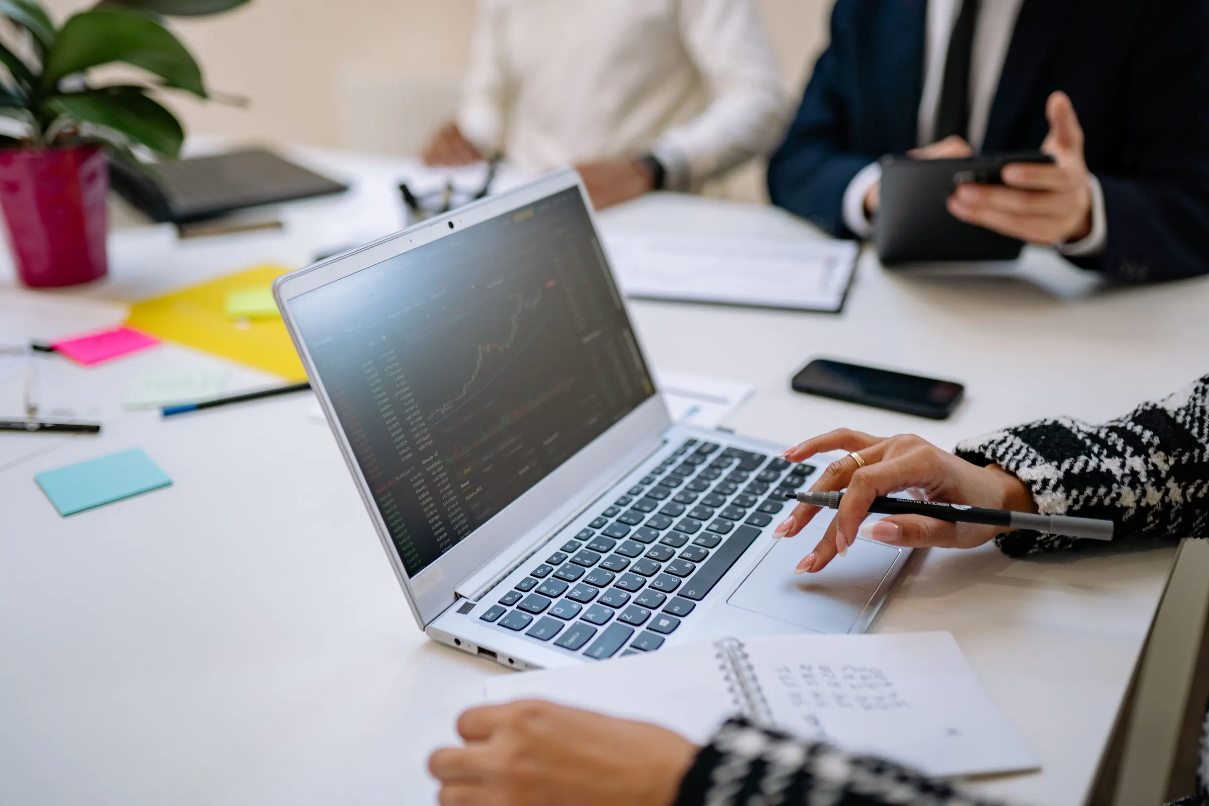 Collega's bespreken een analyse op een laptop, een van hen wijst met een pen naar het scherm