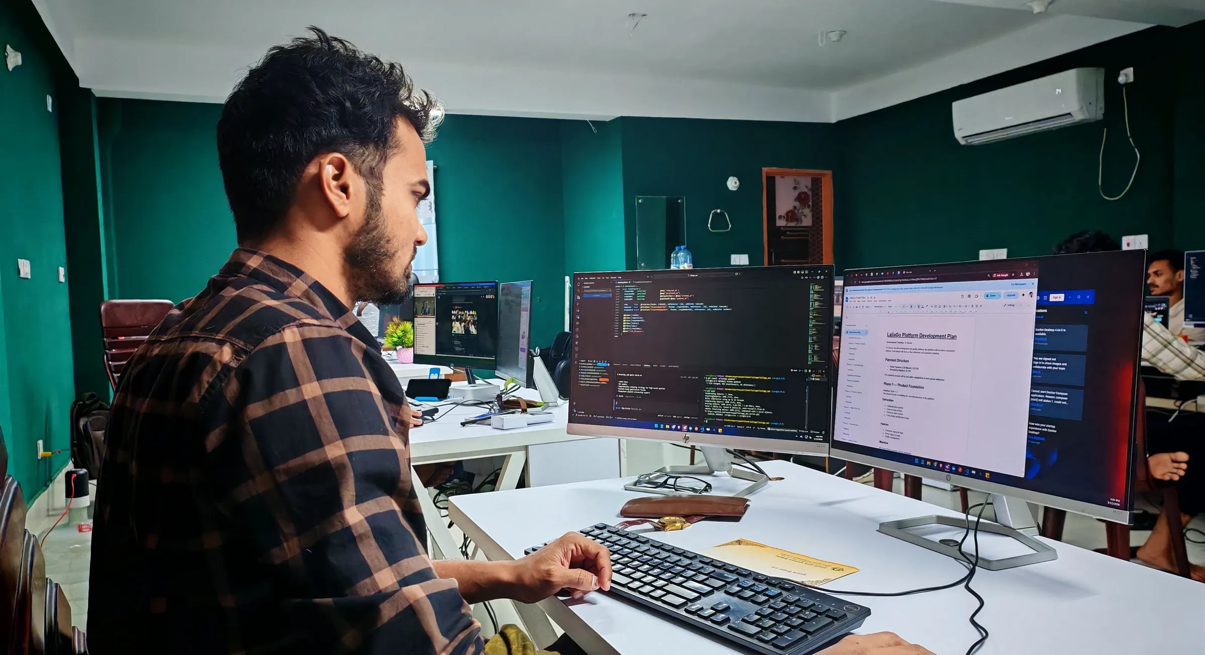 Een developer werkt geconcentreerd achter twee beeldschermen met code