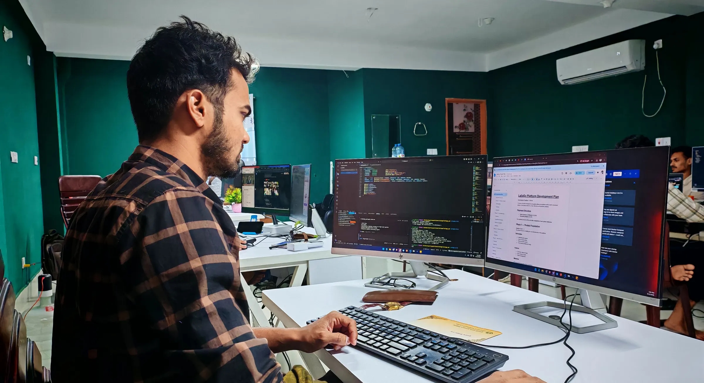Een developer werkt geconcentreerd achter twee beeldschermen met code