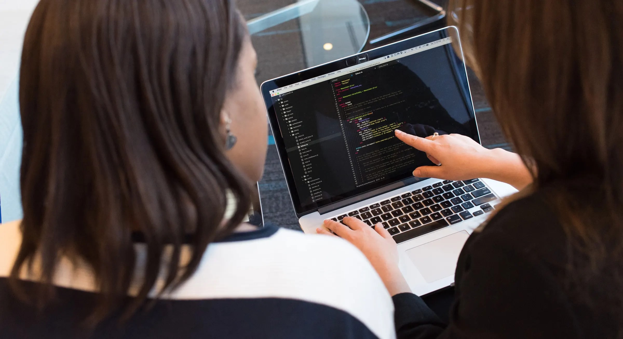 Twee collega's bekijken samen code op een laptop