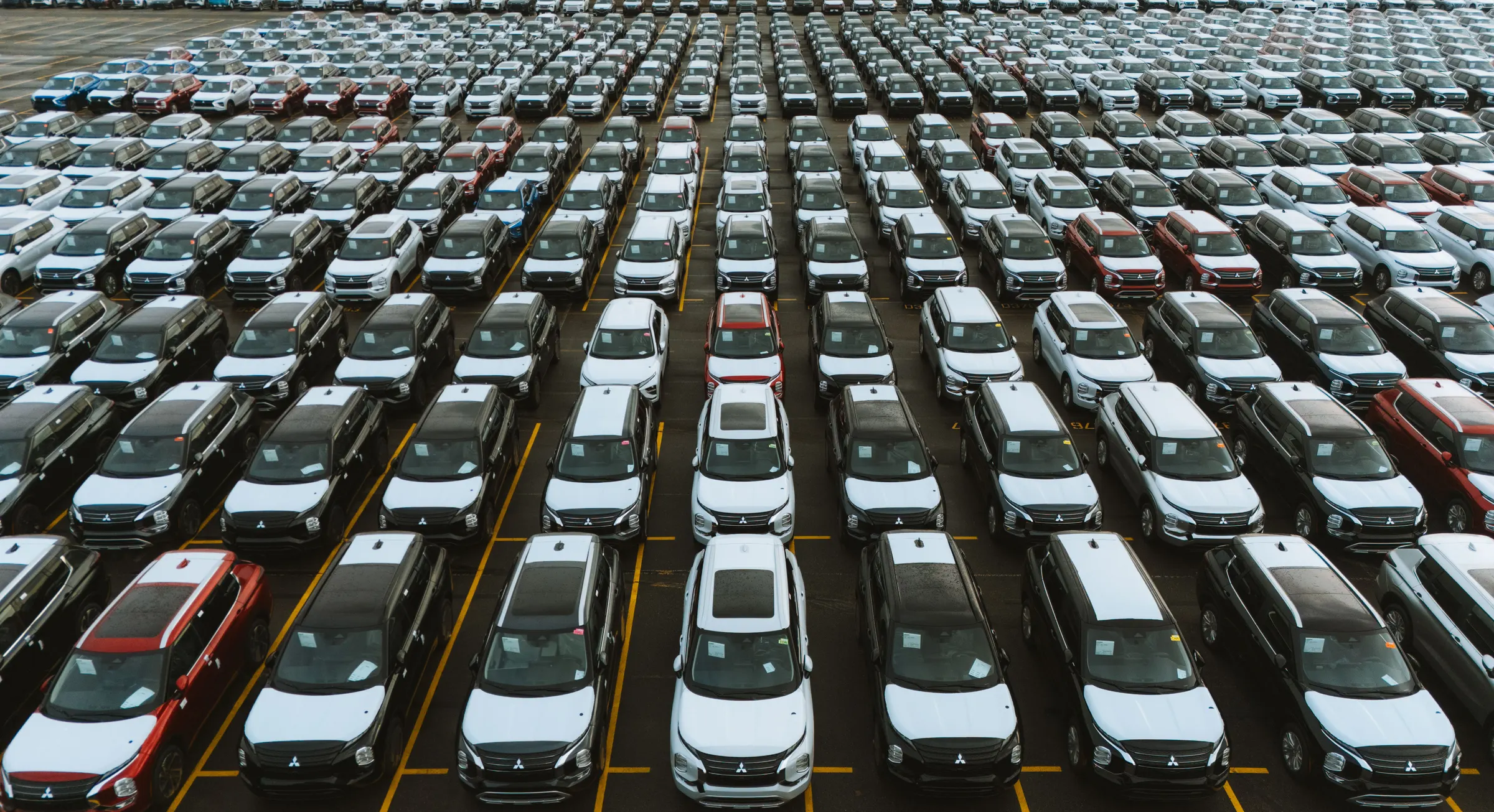 Rijen nieuwe auto's op een overslagterrein, van bovenaf gezien